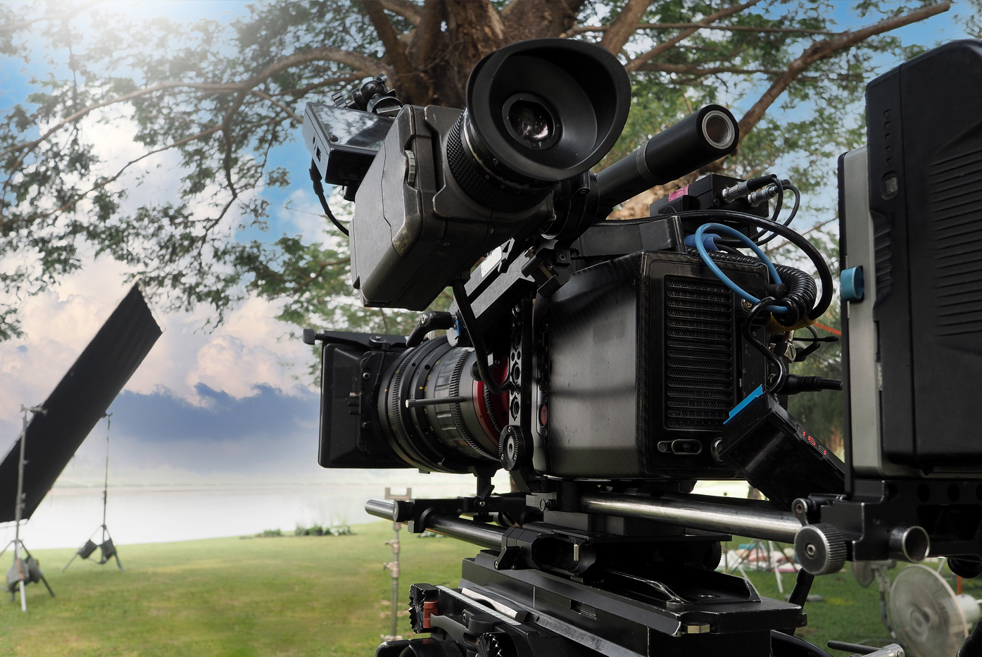 Movie Camera. Behind The Video Camera That For Recording Film Commercial Or Movie At Outdoor Location. 35 Mm Film Styled 4k Digital Camera And Tripod Dolly Crane For Video Production. Film Industry.